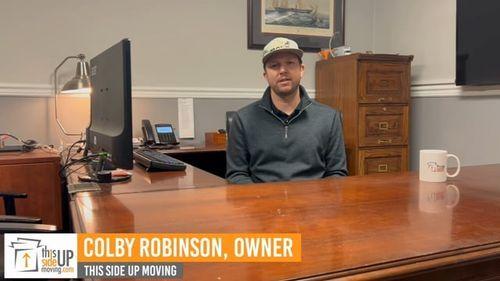 Colby Robinson, owner of This Side Up Moving, seated at a desk in an office setting, discussing moving services and marketing strategies.