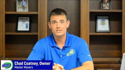 Chad Coatney, owner of Master Movers, speaking in a professional setting with awards on display, promoting effective moving services.